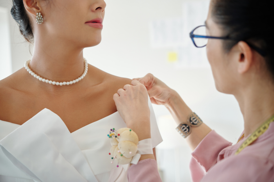 Seamstress pinning wedding dress during bridal fitting