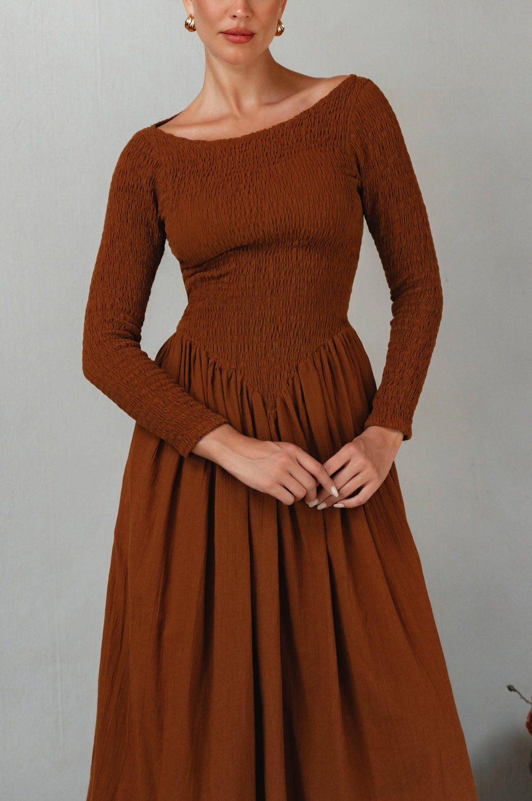 Brown smocked dress worn by a model against a plain background