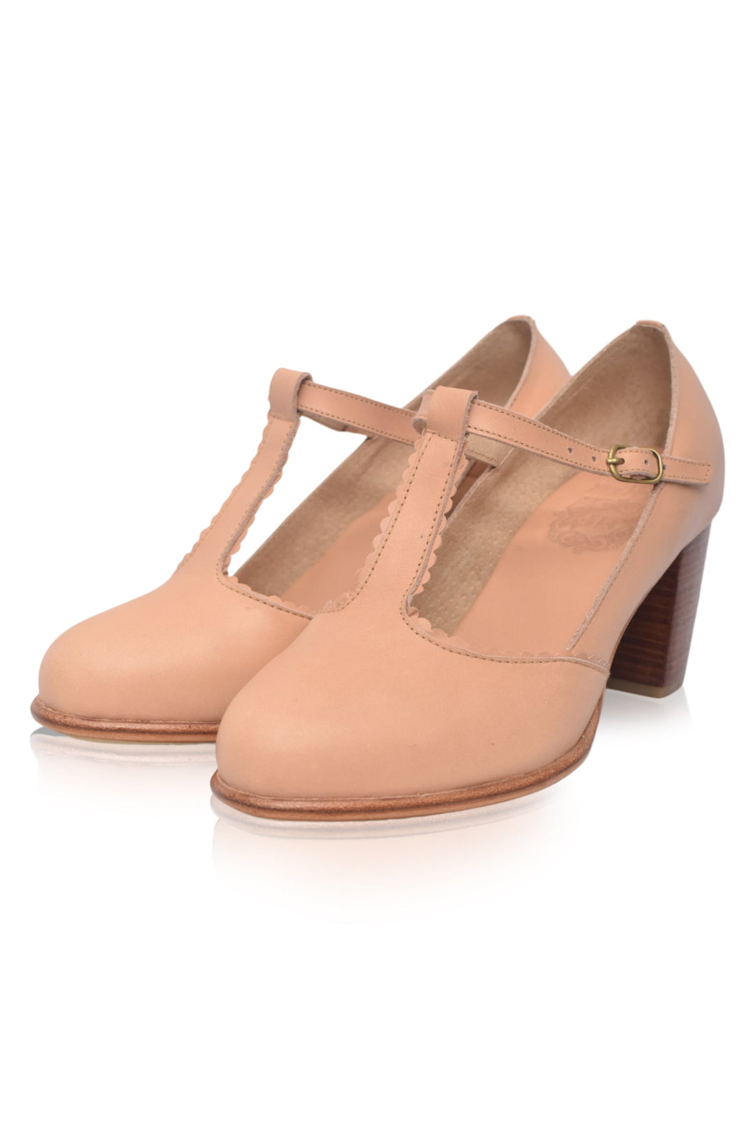 Pair of beige high-heeled shoes with T-straps on a white background