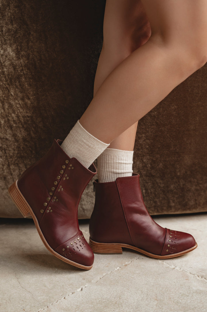 Brown leather ankle boots worn with white socks on a neutral background