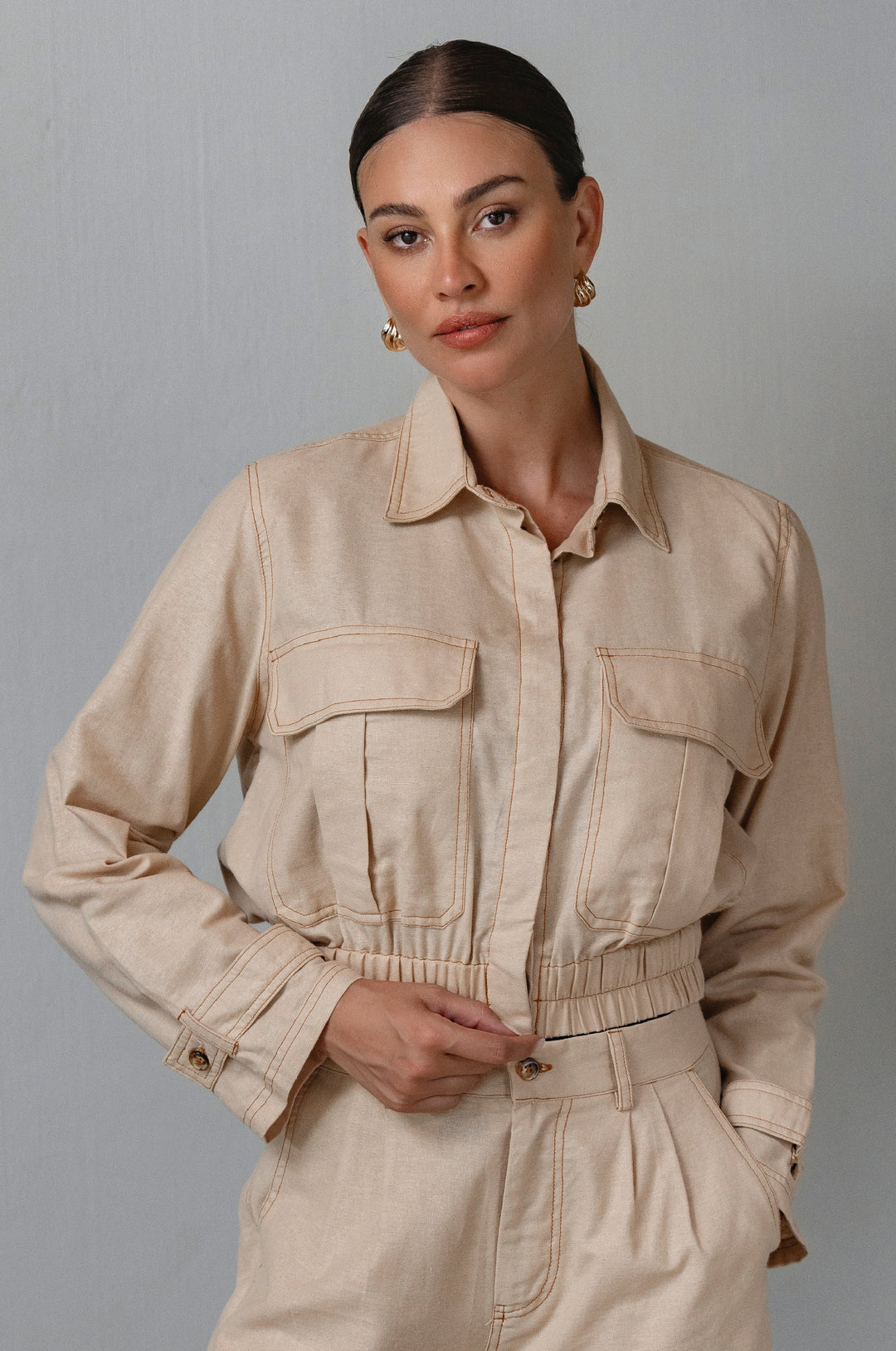 Woman wearing a beige jacket against a plain background