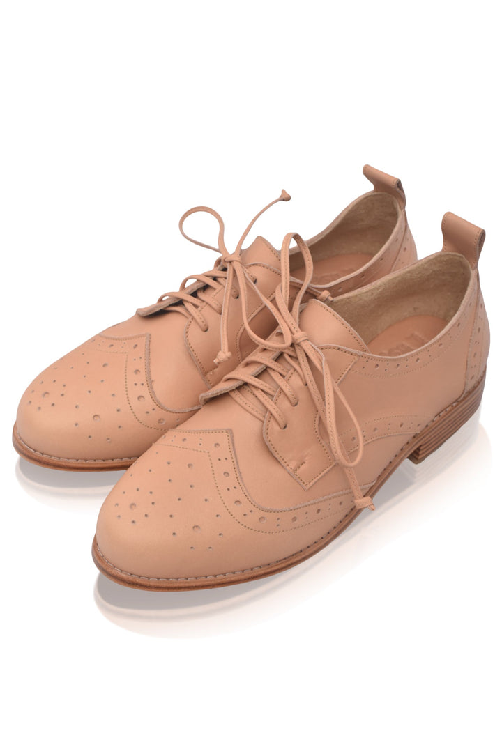 Pair of beige brogue shoes on a white background
