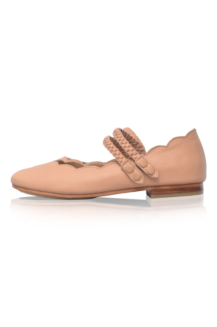 Nude-colored ballet flat shoe with decorative strap and scallop edges