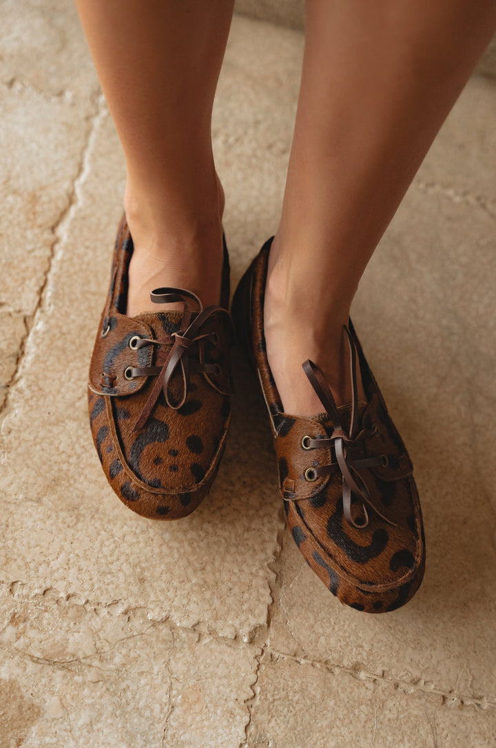 Brown leather shoes with decorative elements on a stone floor