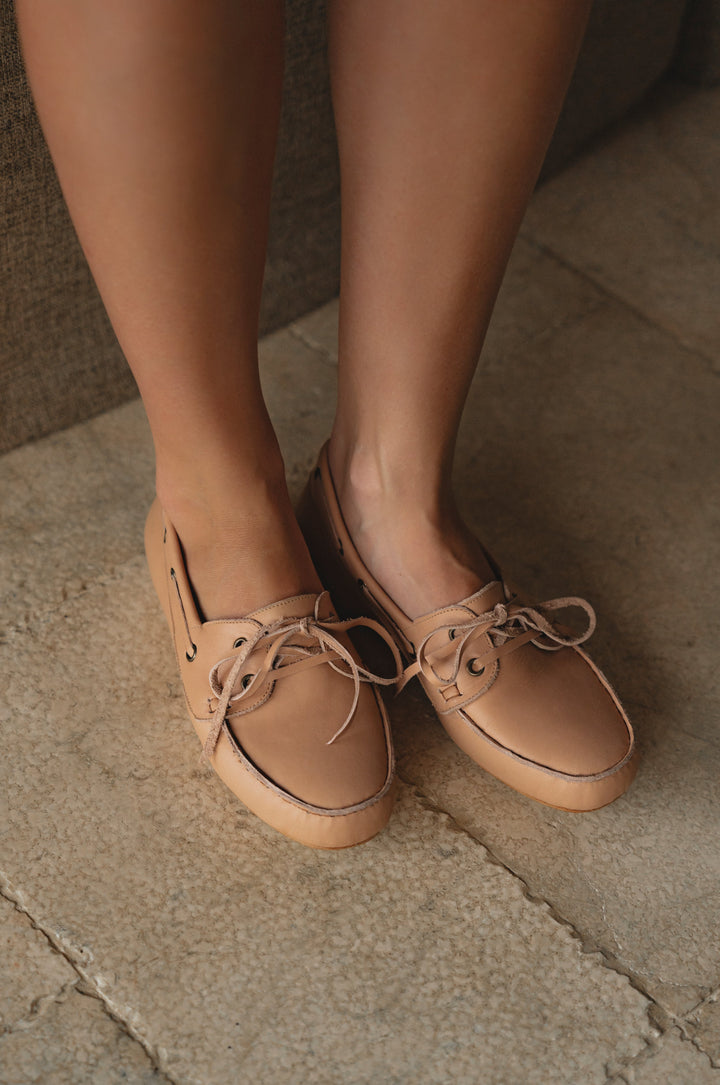 Tan leather shoes worn by a person on a stone floor