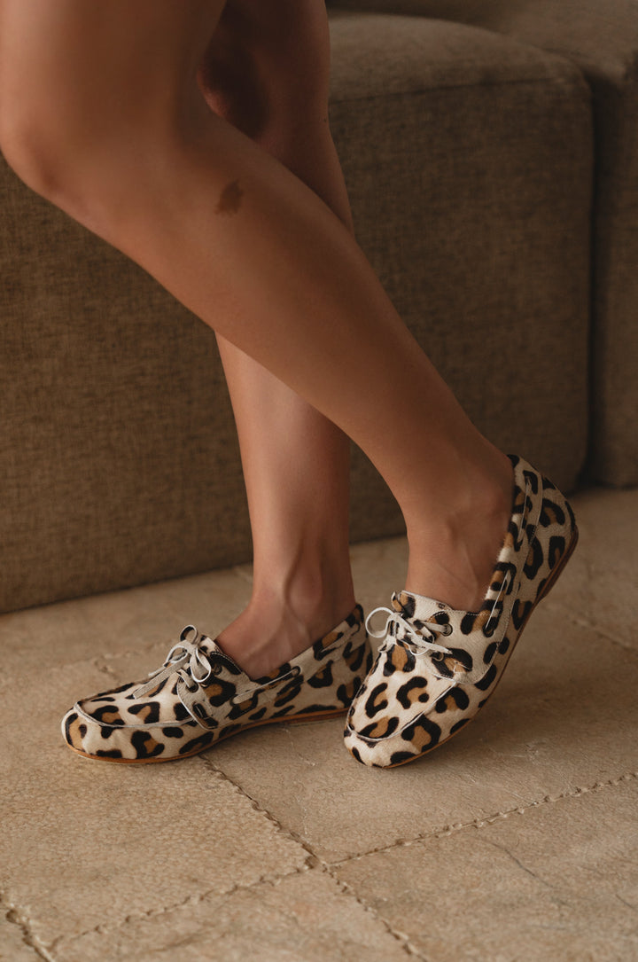 Person wearing leopard print shoes on a neutral background