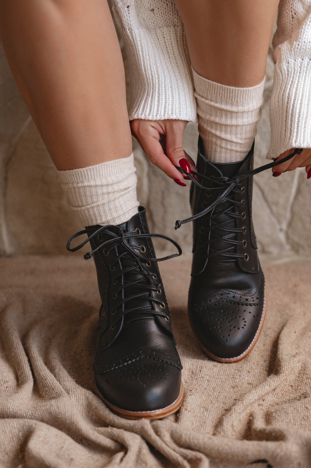 Person wearing black boots and white socks on a textured surface