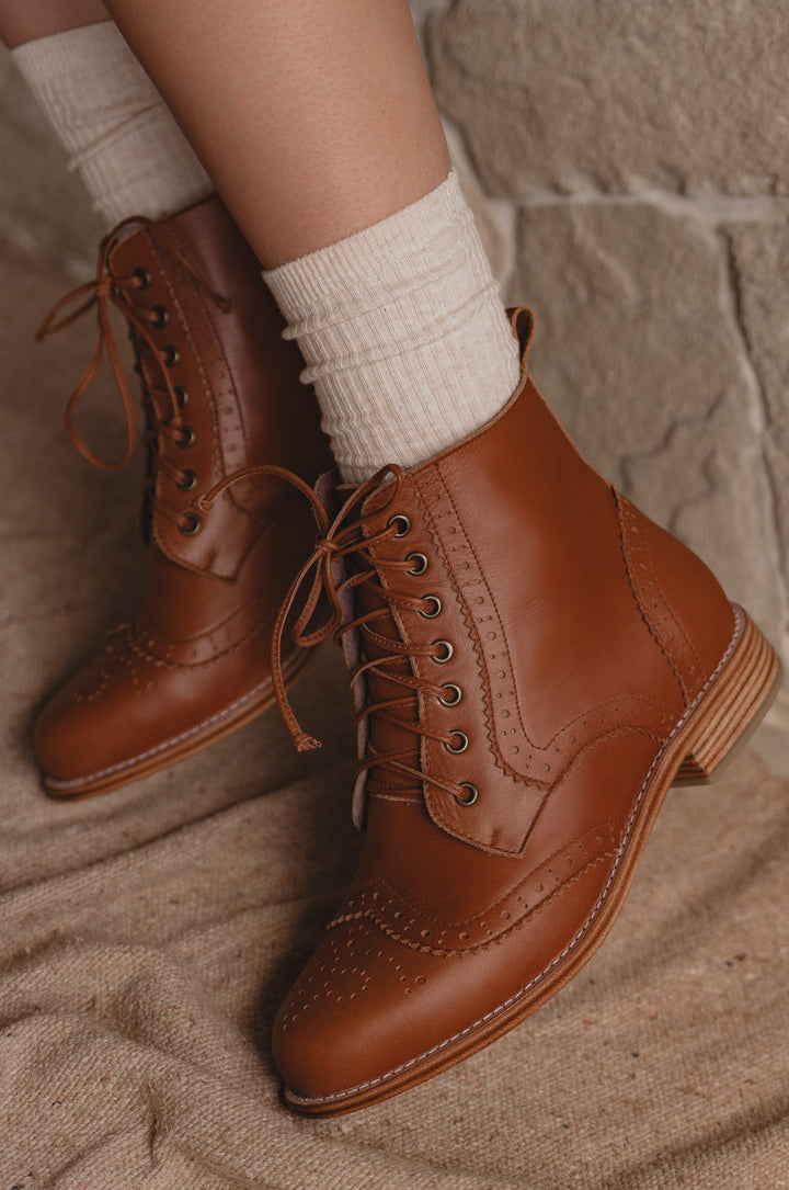 Brown leather boots with white socks on a stone surface