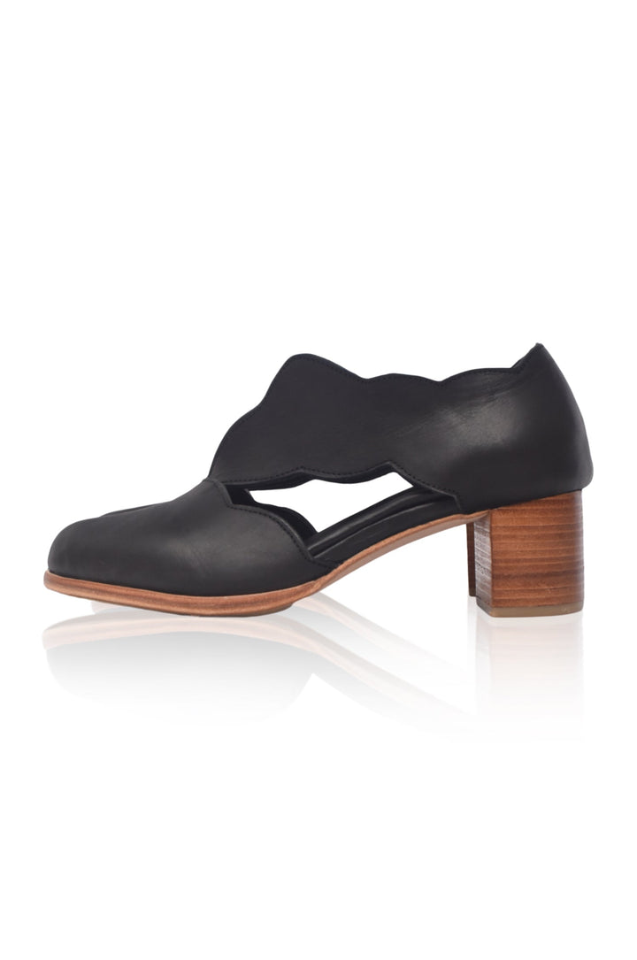 Black leather shoe with wooden heel on a white background